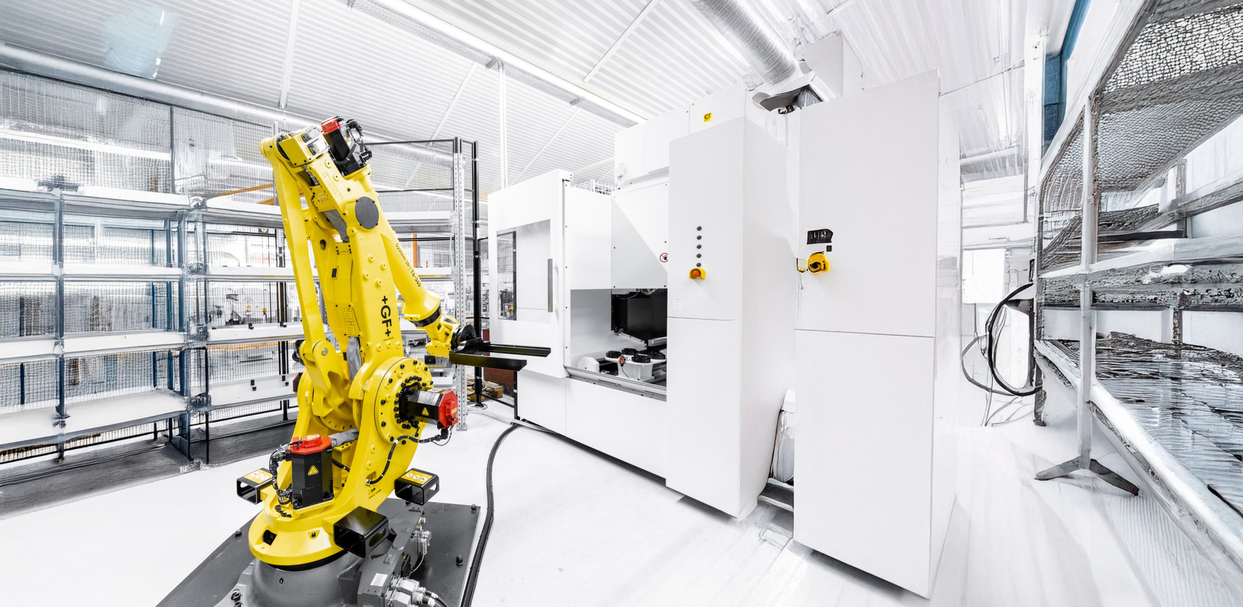 Gelber Roboterarm steht in einer CNC Anlage für mechanische Fertigung in einer sauberen und gut strukturierten Produktionshalle PWB AG