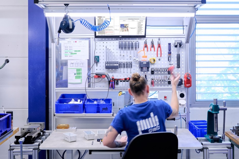 Frau an Montageplatz greift nach Werkzeug an der Wand PWB AG